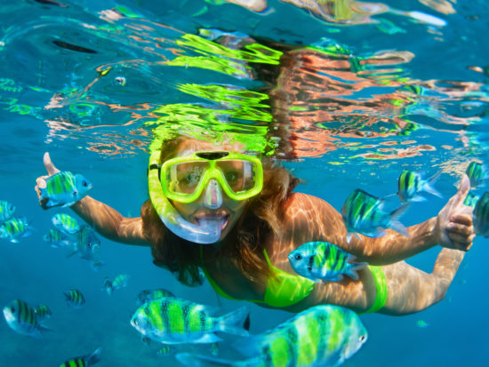 Happy family - girl in snorkeling mask dive with tropical fishes in coral reef sea pool. Travel lifestyle, water sports outdoor adventure, underwater swimming on summer beach holiday with kids.